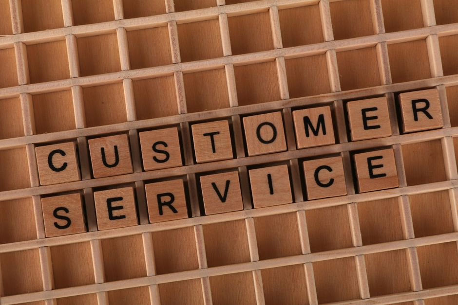 Wooden blocks forming the phrase 'Customer Service' placed inside a wooden grid, symbolizing support and assistance.